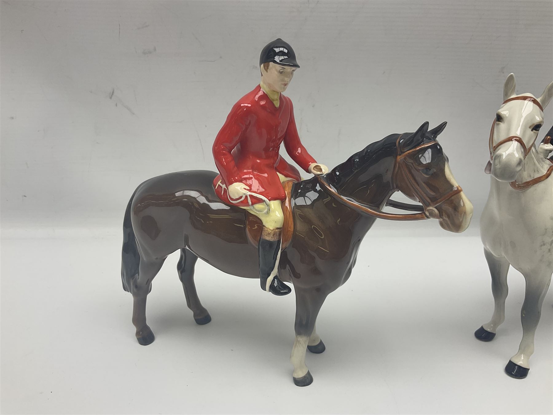 Beswick hunting group, comprising huntswoman on grey horse no 1730, huntsman on brown horse no 1501, fox figure no 1440 and eight fox hounds, all with printed marks beneath (11)