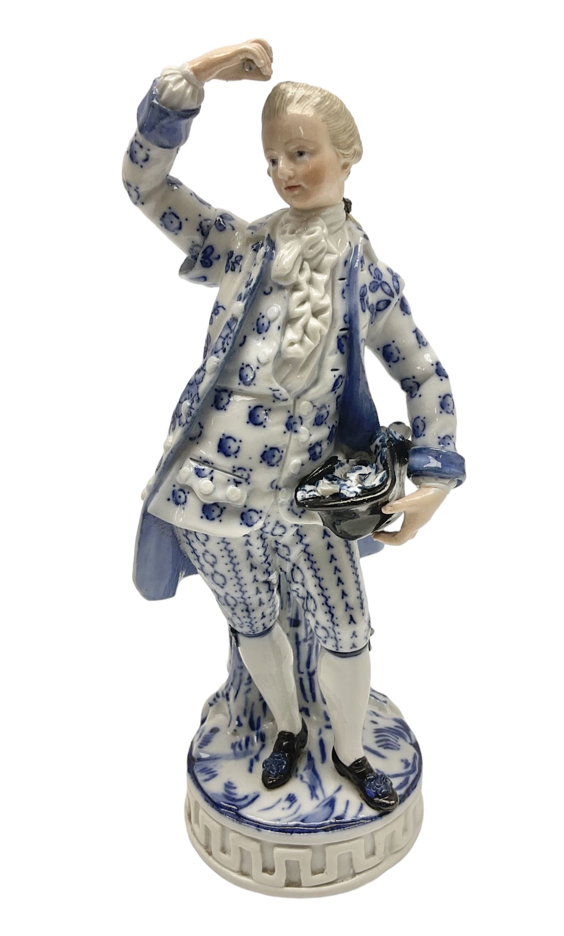 Meissen blue and white figure, modelled as a gentleman holding a hat of flowers, raised upon Greek key design base, with blue crossed swords and impressed C 73 and 149 marks beneath, H18cm