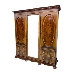 James Shoolbred & Co. London - Edwardian inlaid mahogany triple combination wardrobe, projecting dentil cornice over bevel glazed door, two figured oval panelled doors and four drawers, the central compartment fitted with linen slides and drawers, satinwood banding, on base with shaped apron and bracket feet, with enamel plaque 