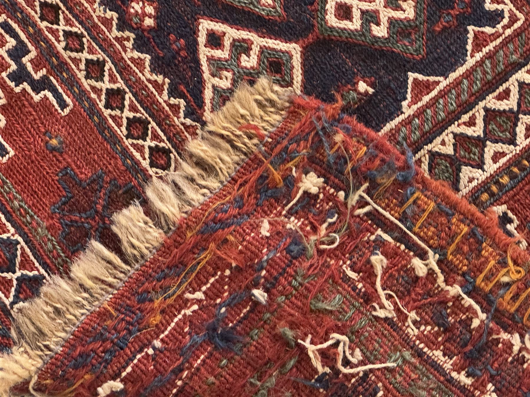Persian-style wool rug, cream field with floral and geometric motifs, wide floral border (74cm x 142cm); Persian wool rug, beige field with dense floral patterns, narrow floral border (70cm x 144cm); Tribal wool rug, red and navy with diamond motifs (96cm x 60cm); Persian pictorial wool rug, black field with vase, birds, and floral border (70cm x 73cm)