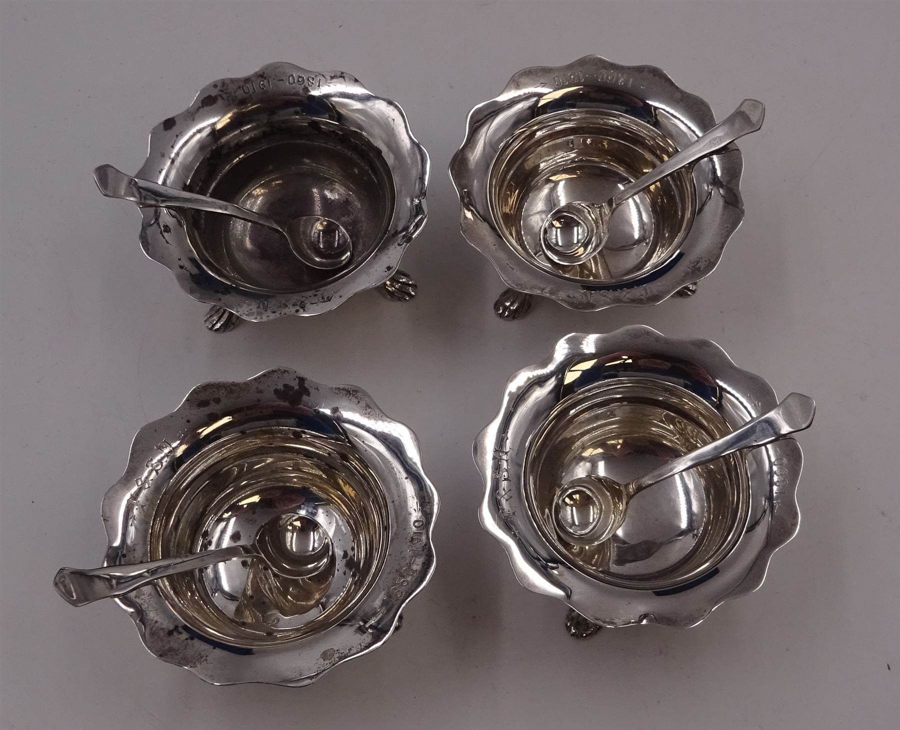 Set of four Edwardian silver open salts, of circular form, each with later personal engraving to scalloped rim and upon three pad feet, together with four matching silver salt spoons, hallmarked James Deakin & Sons, Sheffield 1909, in velvet and silk lined fitted case     