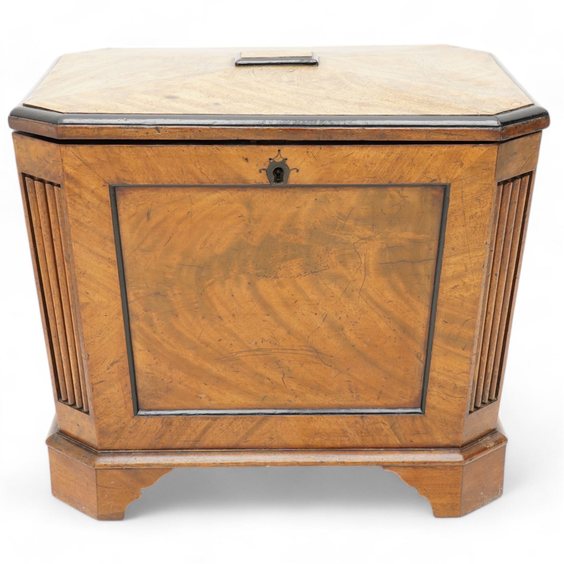 Early 19th century mahogany cellarette, tapering canted rectangular form, the hinged faceted top enclosing fitted interior, panelled front, back and sides with figured mahogany veneers, the canted corner with wide reeded decoration, on canted bracket feet 
