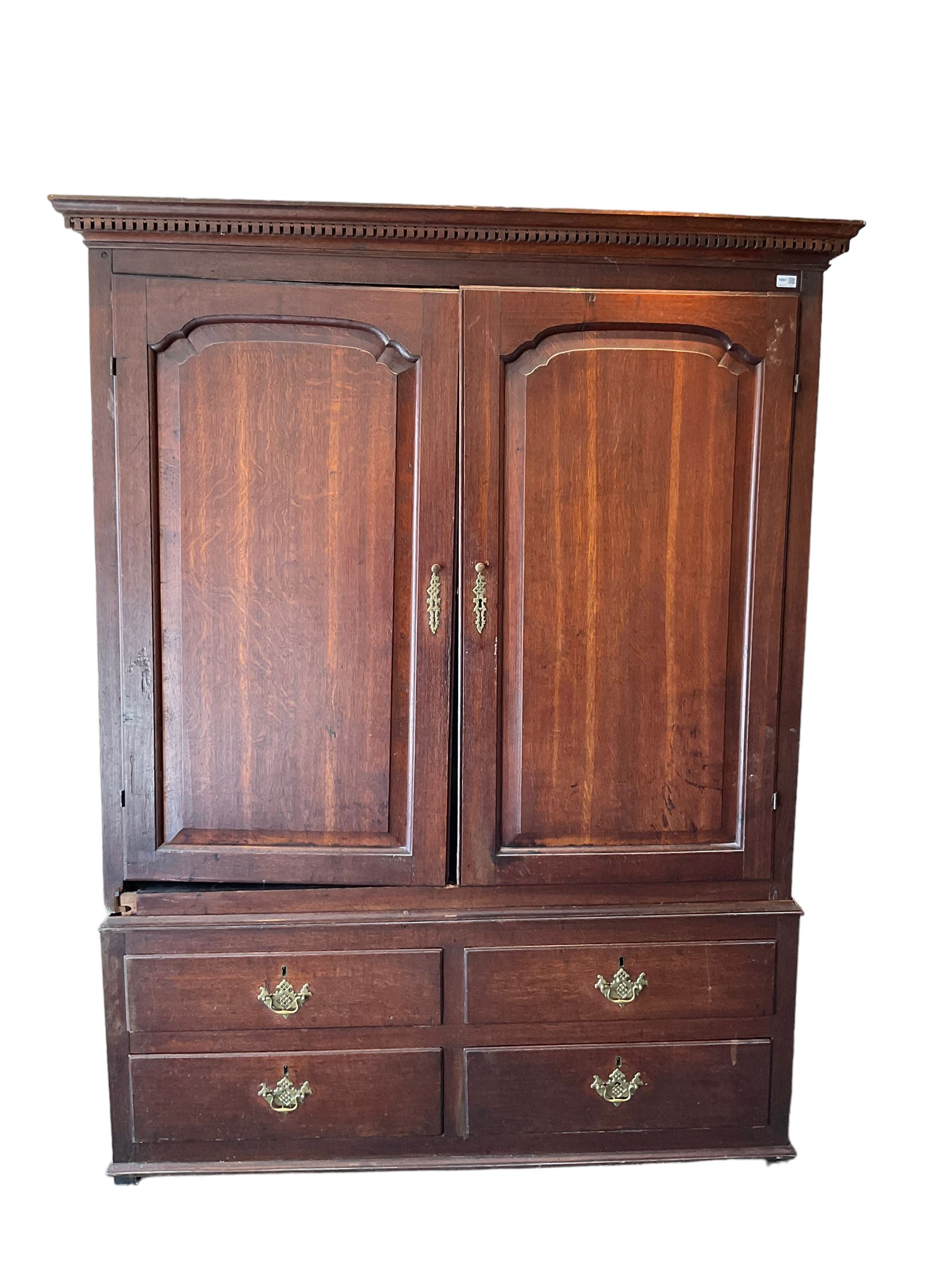 George III oak press cupboard, dentil cornice over two arch fielded panel doors, the base fitted with four drawers with pressed brass handle plates