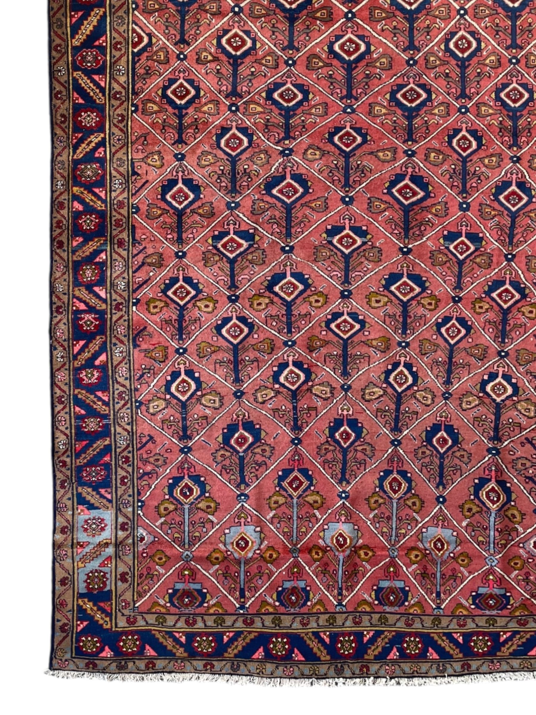 Persian Ardakan crimson ground rug, the field divided by lattice and decorated with stylised tree of life motifs, the border decorated with geometric flower heads, within guard stripes 