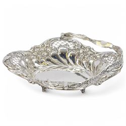 Edwardian silver swing handled basket, of oval form with shaped rim, embossed with floral decoration and with pierced latticework sides, upon four pad feet, hallmarked Chester 1905, maker's mark worn and indistinct