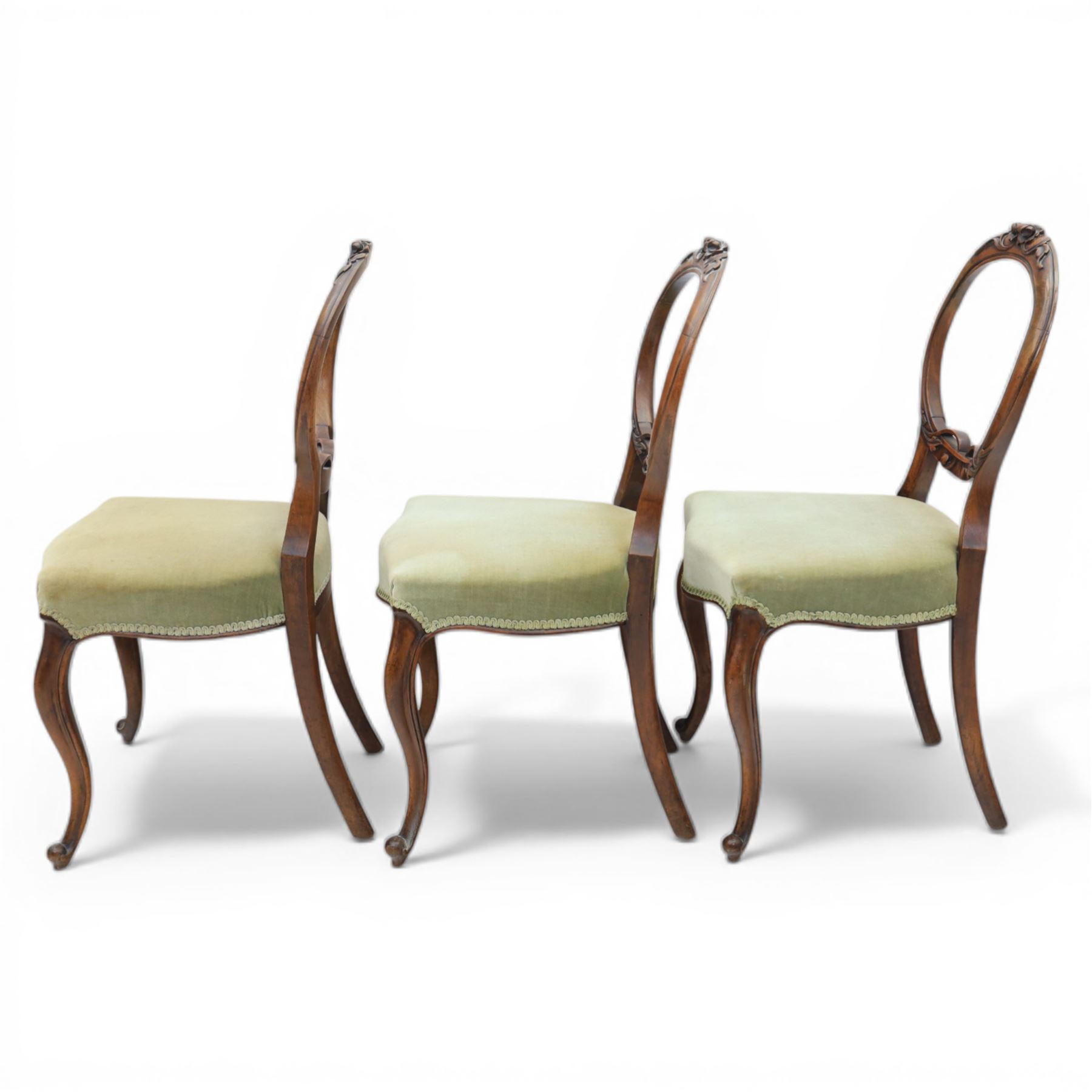 Victorian mahogany dining suite, oval tilt top dining table raised on a quatriform base with paw feet, together with a set of six balloon back dining chairs with green upholstery with cabriole legs 