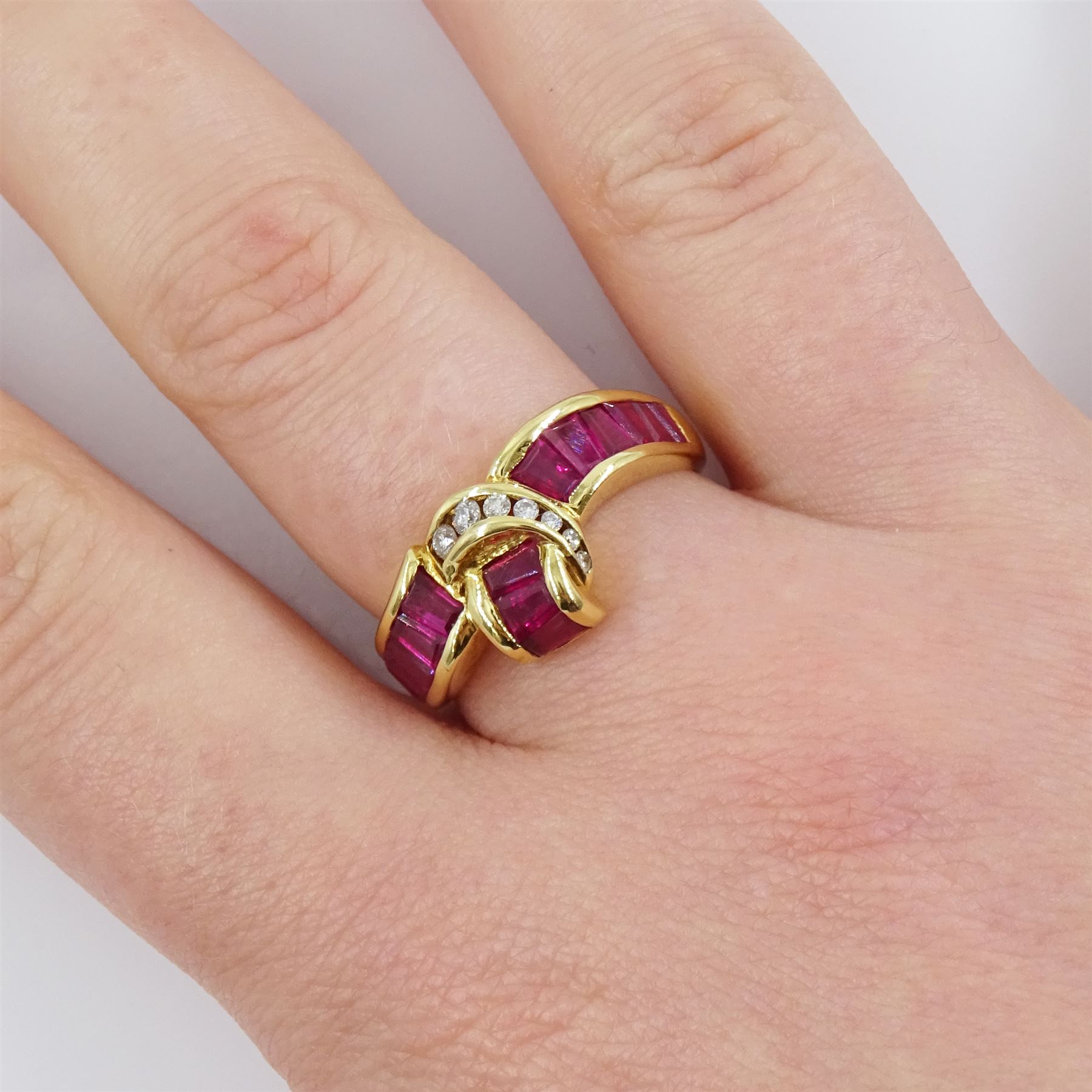 18ct gold ruby and diamond crossover ring, channel set with fifteen calibre cut rubies and seven graduated brilliant cut diamonds