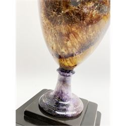 Early 19th century and later Blue John urn, Winnats one vein, of ovoid form with integrated cover and ball finial, upon a spreading circular base, and square stepped black lacquered base, H34.5cm