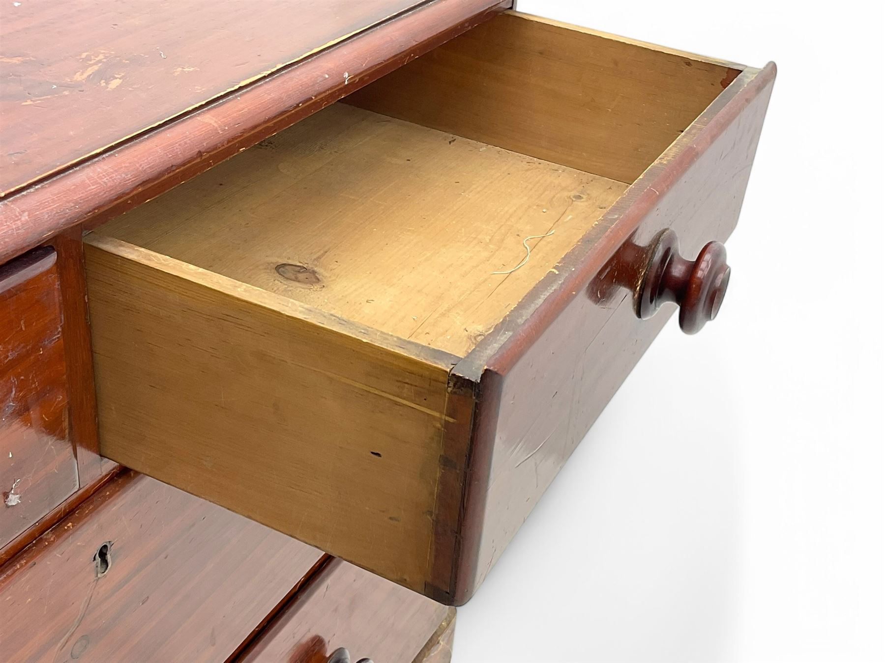 Victorian 19th century stained pine chest of drawers, rectangular top above two short and three long drawers with turned wooden handles, raised on bun feet with castors.