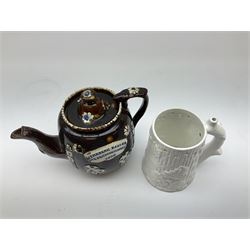 A 19th century Barge Ware teapot, decorated with applied floral sprays and thistles against a mottled brown ground, and plaque detailed Catherine Taylor God Bless Our Home 1890, H18cm, together with a white glazed puzzle mug, H15cm. 