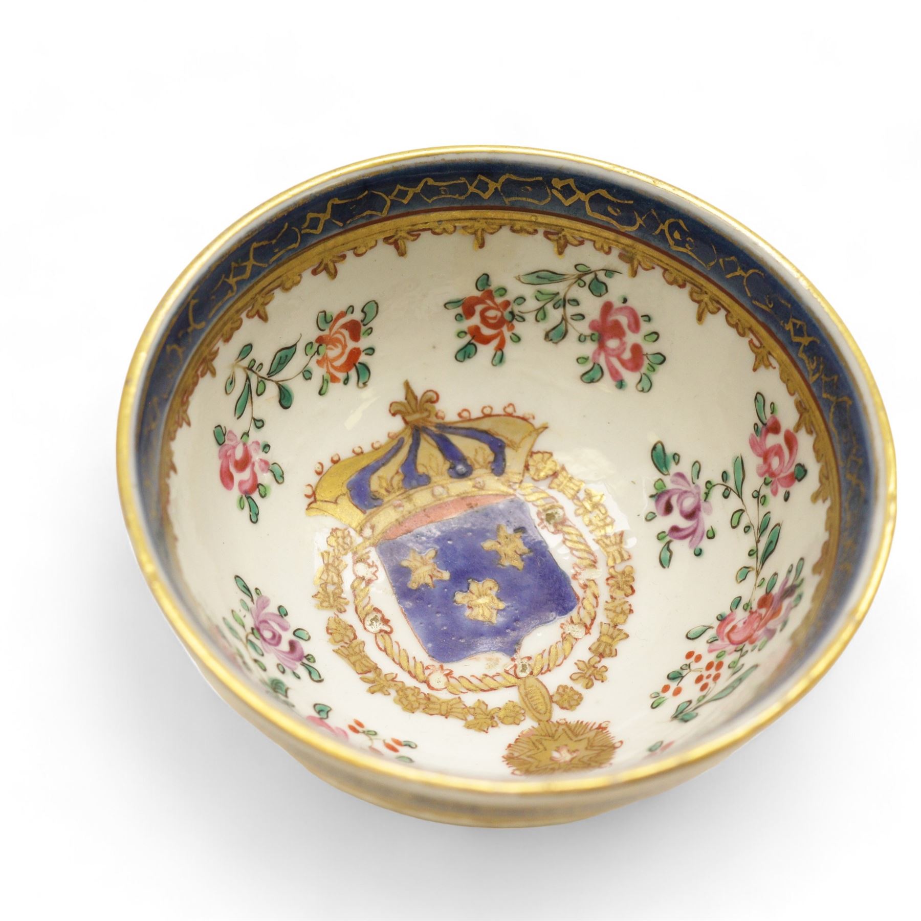 Chinese tea bowl, the enamel decoration depicting floral sprigs within a gilt and blue boarder, with a crowned shield to the centre, together with another bowl and a saucer