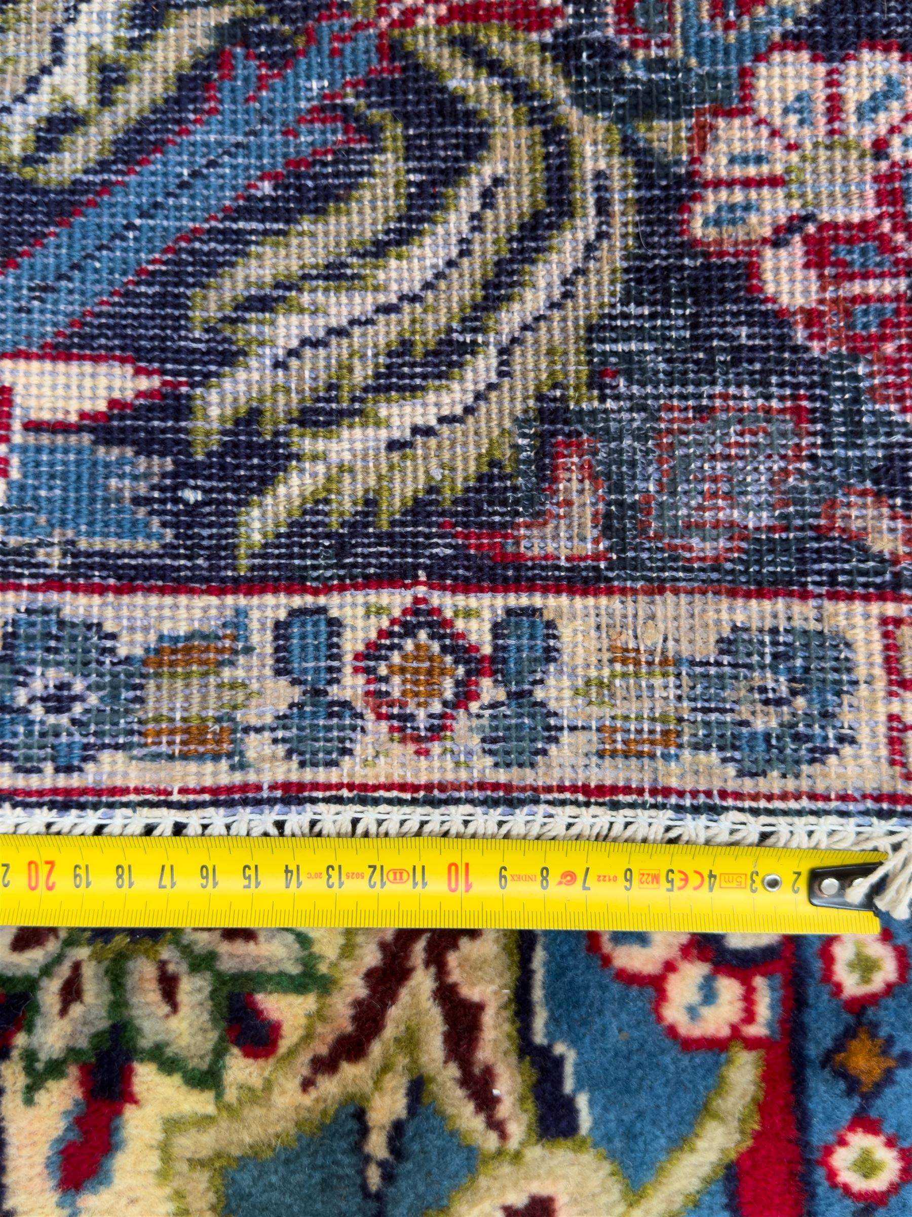 Central Persian Isfahan Carpet, hand-knotted, featuring a bold central rosette medallion on a rich red field, flanked by stylised floral sprays, scrolling foliage and mythical animals, within a broad indigo border decorated with alternating cartouches and flowerheads