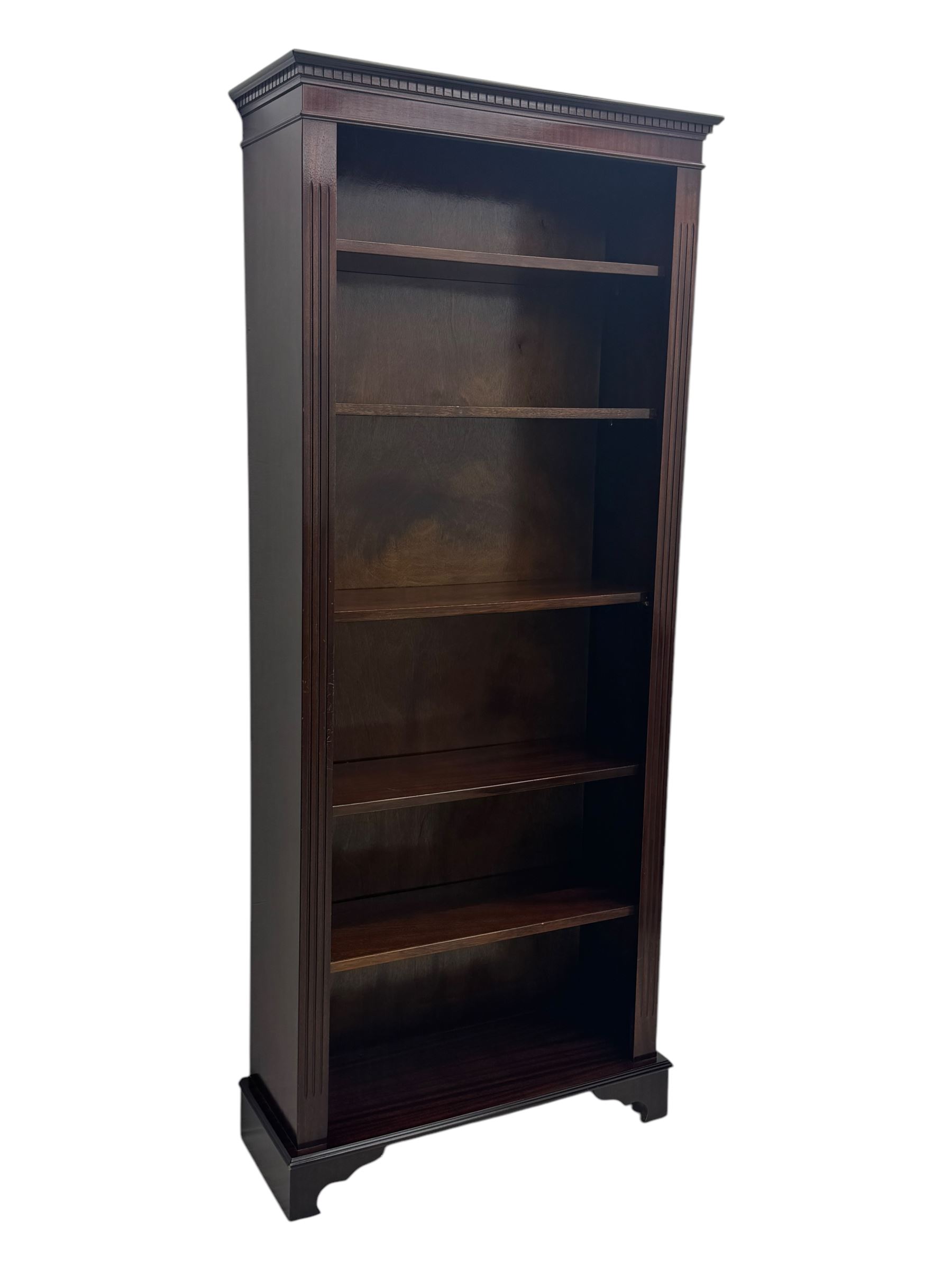 Early 20th century mahogany open bookcase, the rectangular top with dentil moulding, the sides with fluted decoration, fitted with five adjustable shelves, on ogee-moulded bracket supports