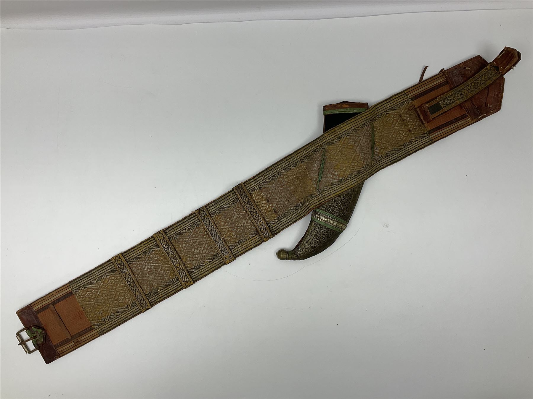 Late 19th century Yemeni Tuza jambiya as worn by religious elite, the 20.5cm curving blade with raised medial ridge, the horn hilt with pique style studwork, in a leather wrapped wooden scabbard with pierced metal mount and leather belt applied with embroidered 'gold' and 'silver' thread work panel; dagger L36cm overall, belt L84cm
