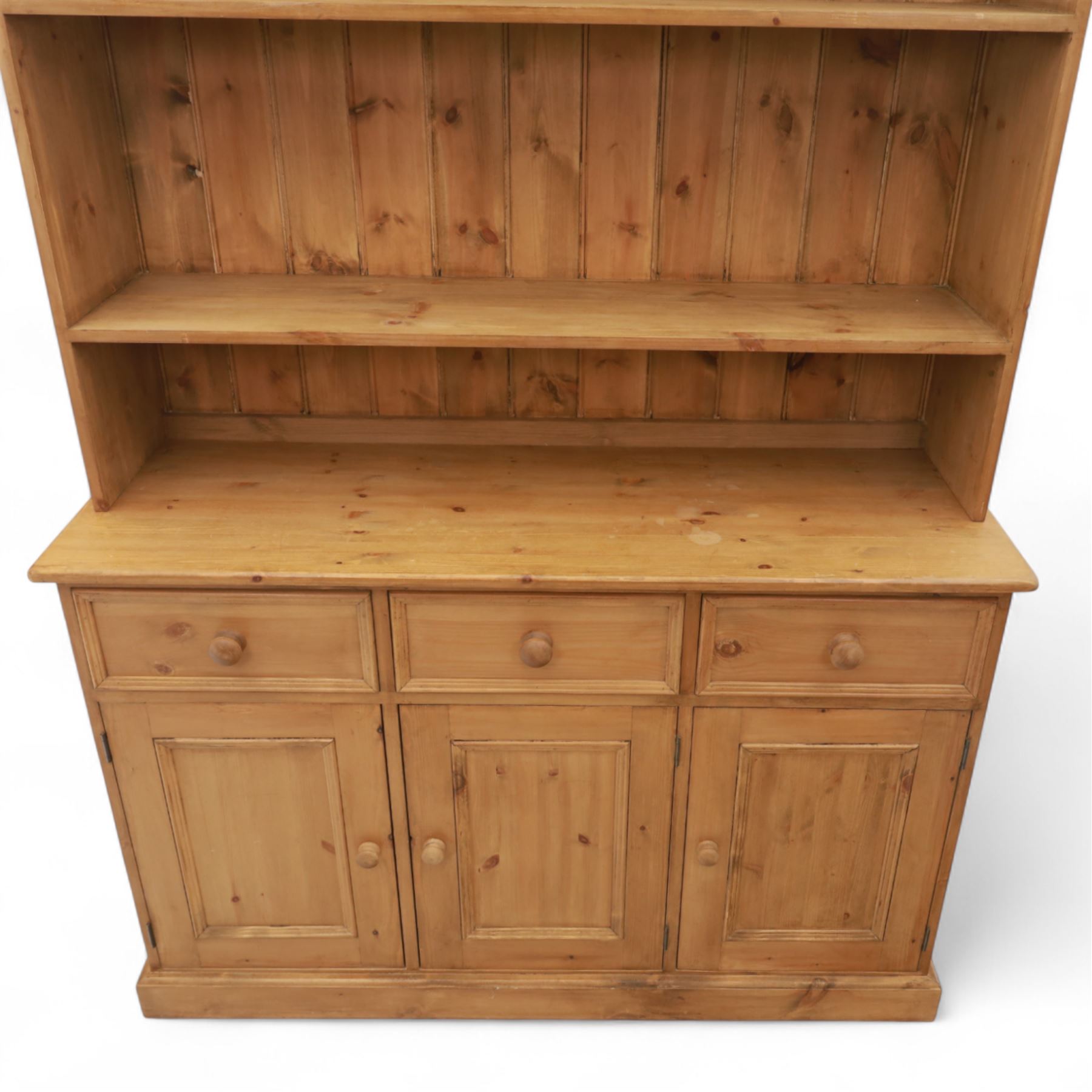 Late 20th century pine kitchen dresser, the upper section with open shelves and tongue and groove back, over a triple cupboard base with three drawers, turned wooden knobs throughout