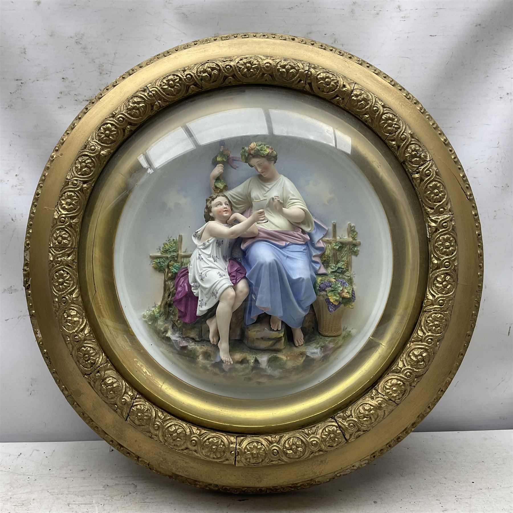 Set of four early 20th century Continental bisque plaques, each of circular form, modelled in high relief as the Four Seasons personified, within gilded circular frames under convex glass, overall D44.5cm