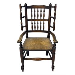 Early 19th century ash armchair, the back with winged spindles extending from a shaped top rail, above a splat of two rows of vertical spindles, with curved arms and a rush seat, raised on turned supports united by double stretchers terminating in castors