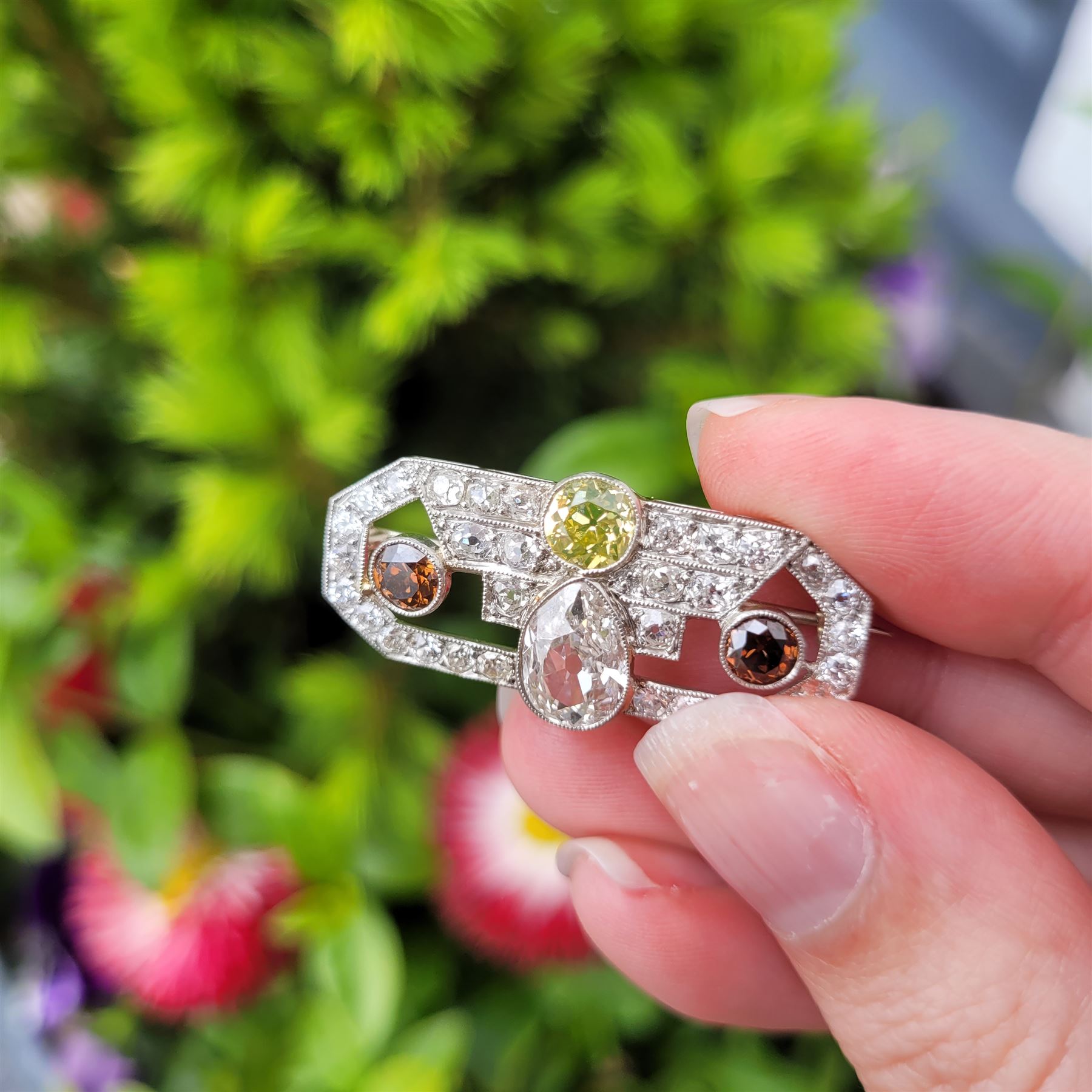 Early 20th century platinum diamond brooch, milgrain set with a pear cut faint brown diamond of approx 1.50 carat, an old cut fancy yellow / green diamond of approx 0.70 carat, and two old cut fancy orange / brown diamonds of approx 0.40 carat and 0.35 carat, surrounded by old cut white diamonds in an openwork setting, total white diamond weight approx 1.45 carat