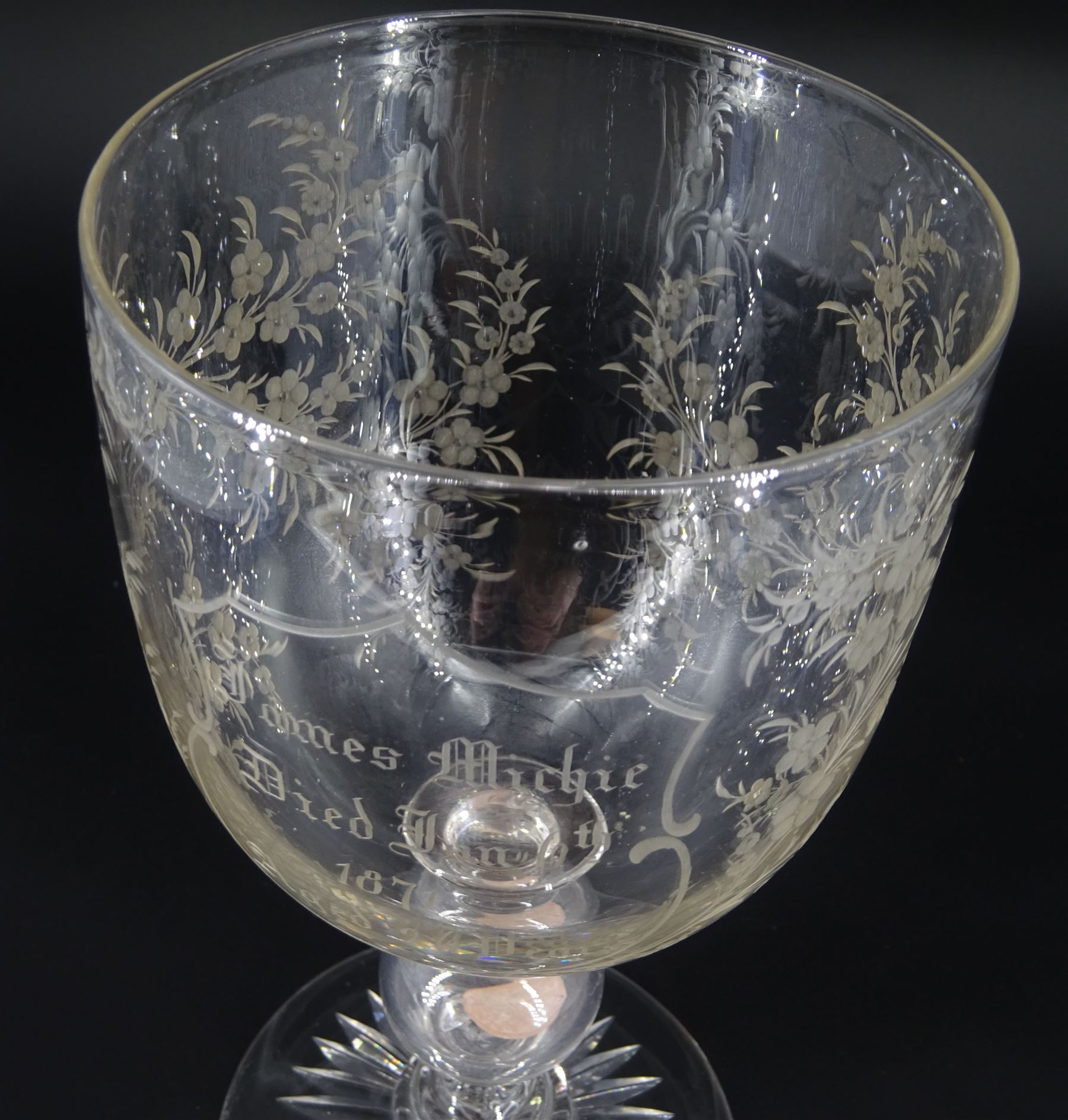 Late 19th century oversized glass goblet, the bowl engraved with cartouche containing dedication 'Jams Michie Died Jan 6th 1871 Aged 26 Years', surrounded by foliate detail, upon a hollow knopped stem containing a silver Victorian 1861 threepence and circular foot with star cut base, H19.5cm