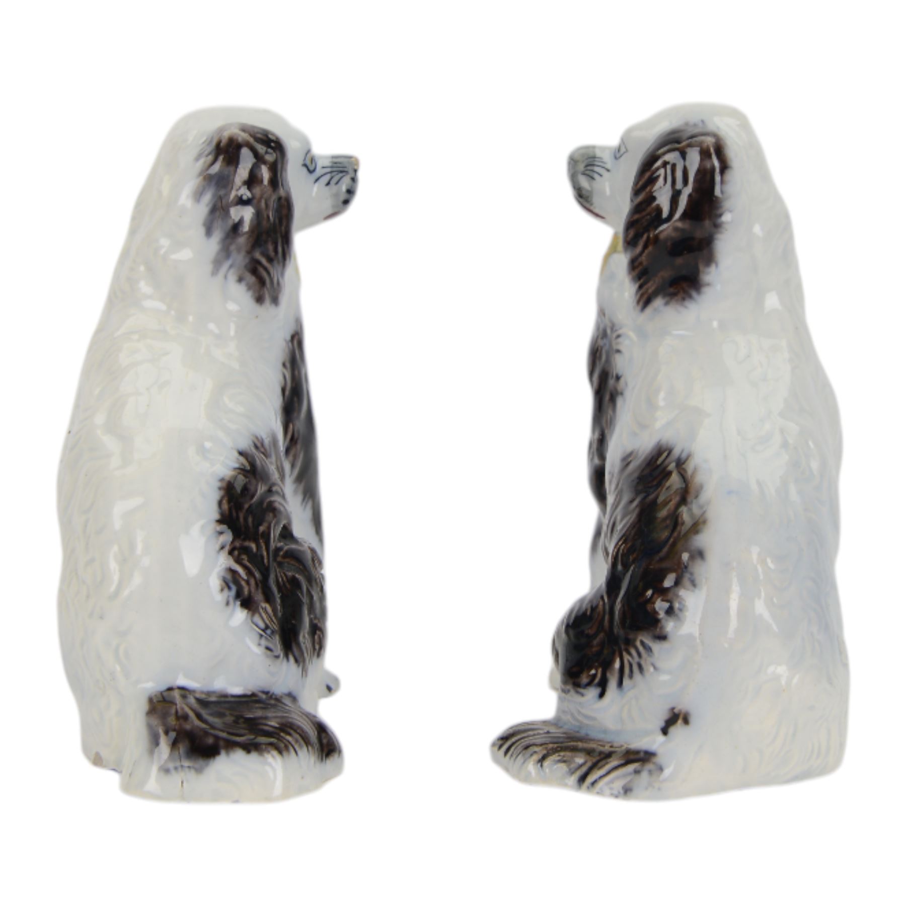 Pair of 19th century slip moulded pottery spaniels, circa 1840-1850, possibly Scottish, modelled with free standing forelegs and moulded fur with dark brown detailing and yellow glazed collars and padlocks upon a white ground, H17.5cm