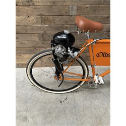 Fully restored vintage advertising bicycle with 2 stroke petrol engine, orange frame, tan leather seat