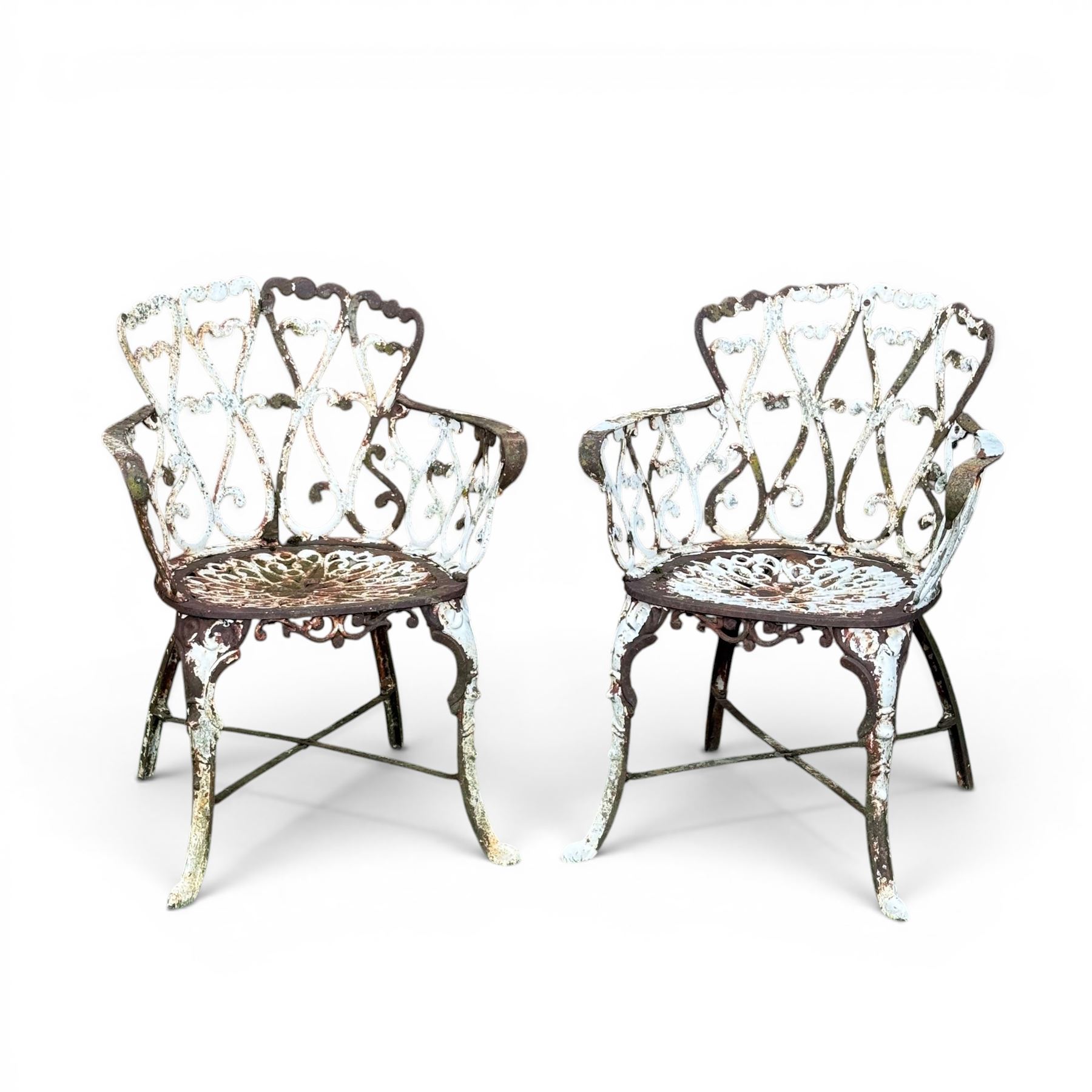 Pair of late 19th century painted cast iron garden chairs, open scroll and heart backs, ornate circular seat, raised on cabriole legs with X stretcher