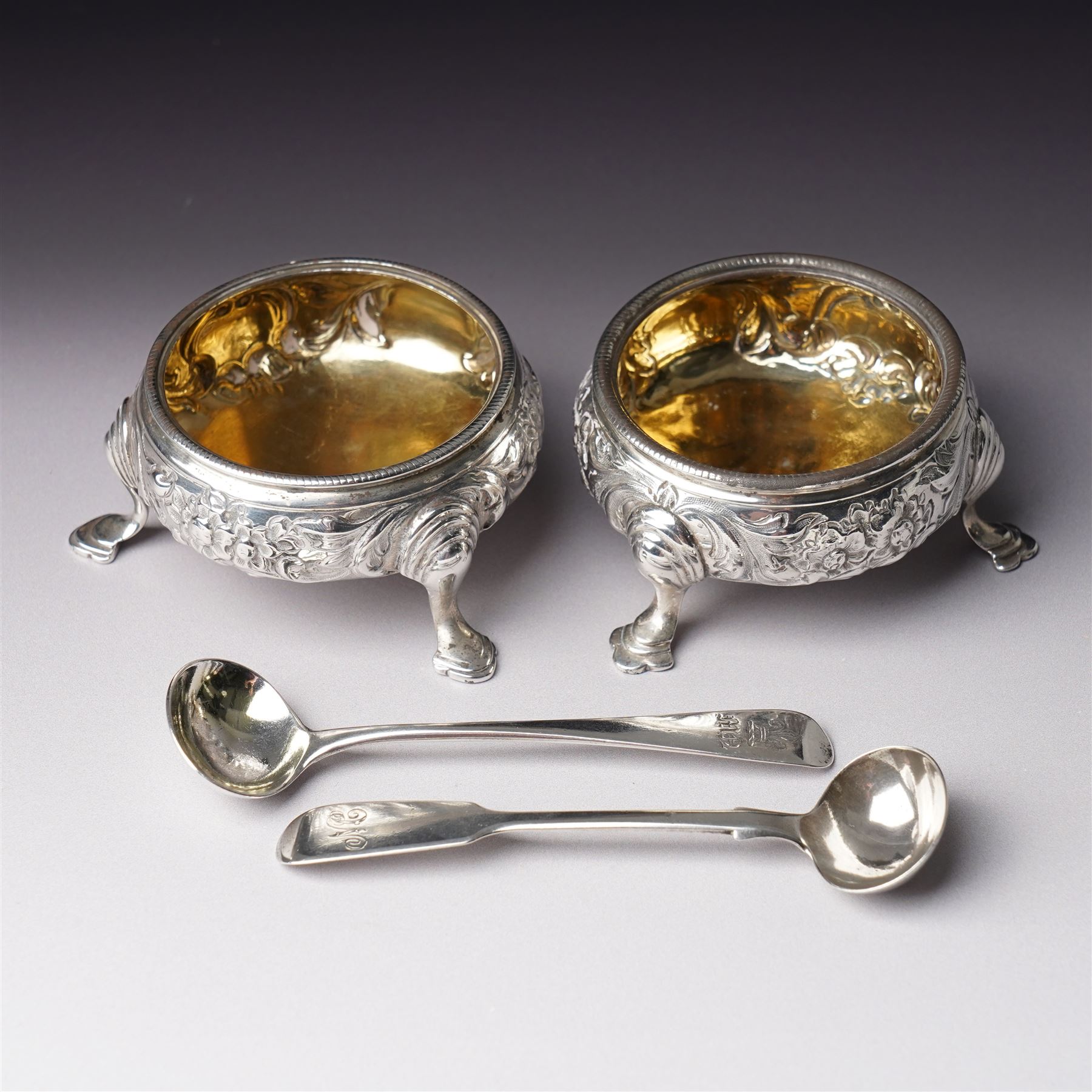 Pair of George III silver circular salts with gilded interiors and embossed decoration and two 19th century condiment spoons, one by Peter and Ann Bateman 