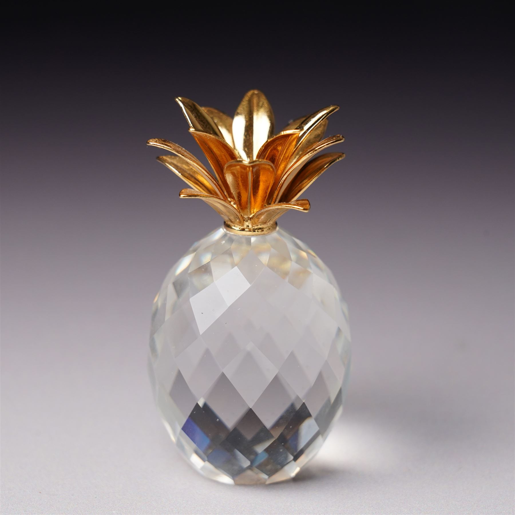 Pair of Swarovski Crystal candlesticks, boxed, together with two paperweights in the form of pineapples with gilt mounts, a large and small example, boxed (4)