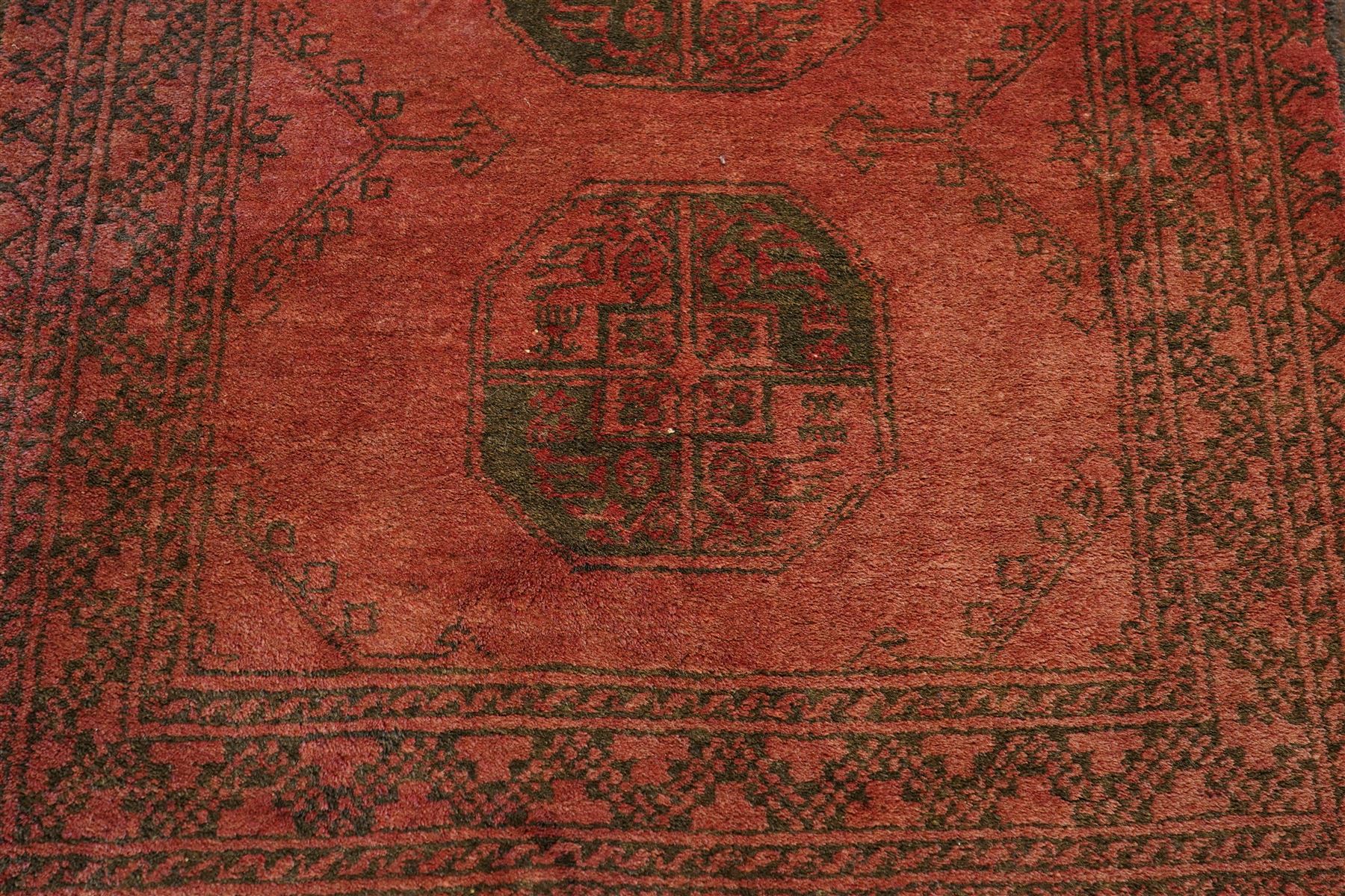 Antique Persian Bokhara red ground runner rug, repeating Gul pattern, surrounded by borders, with fringed ends