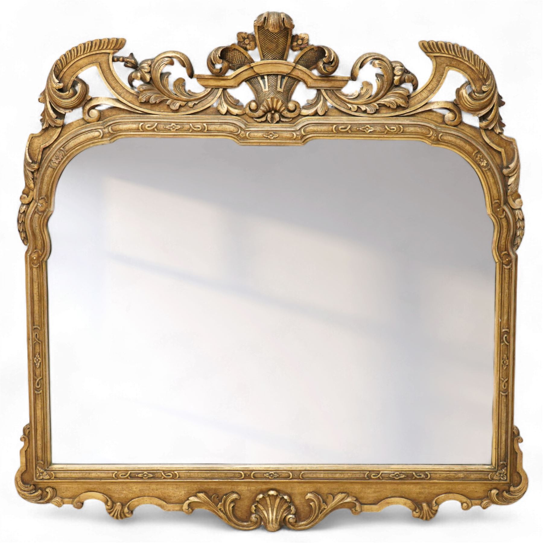 Georgian design giltwood overmantel mirror, arched rectangular plate within a moulded frame, the cresting carved with scrolling acanthus and shell motifs, trailing foliate decoration continuing to the shoulders and lower apron