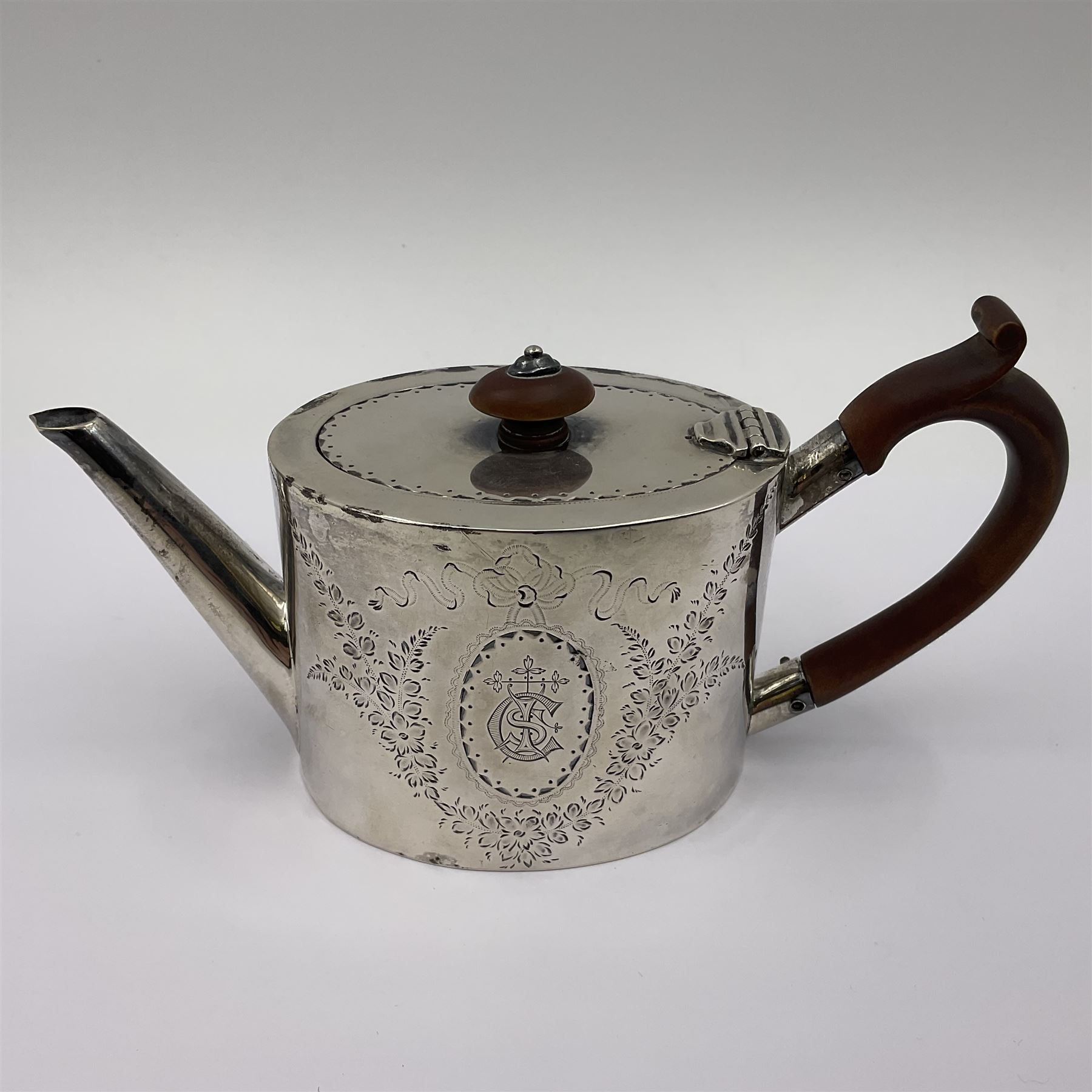 George III silver bachelors teapot, of oval form with wooden scroll handle and finial, the body chased with armorial crest and ribbon swag and foliate detail, hallmarked Samuel Godbehere & Edward Wigan, London 1793, including handle H9cm