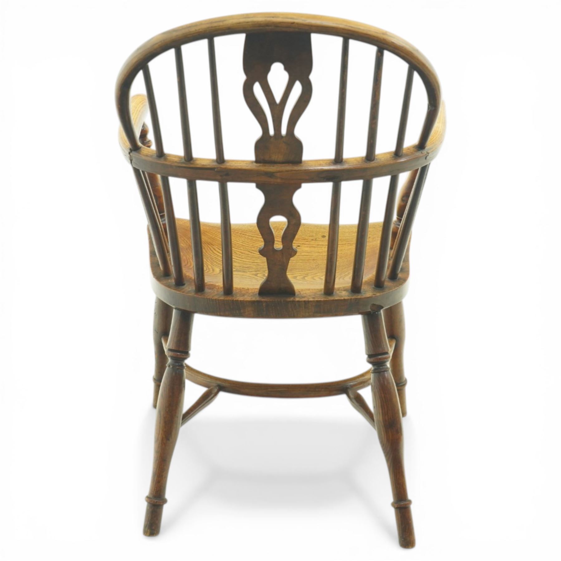 19th century low back elm Windsor armchair, hooped back with pierced central splat and radiating spindles, shaped arm bow over saddle seat, on turned supports united by crinoline stretcher