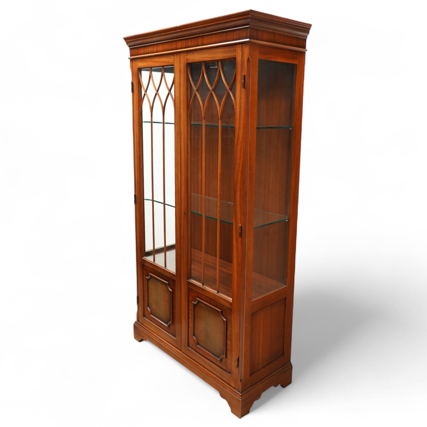 20th century Georgian design mahogany display cabinet with illuminated interior, dentil moulded cornice over twin astragal glazed doors enclosing glass shelves, lower panelled cupboard doors, on shaped bracket feet