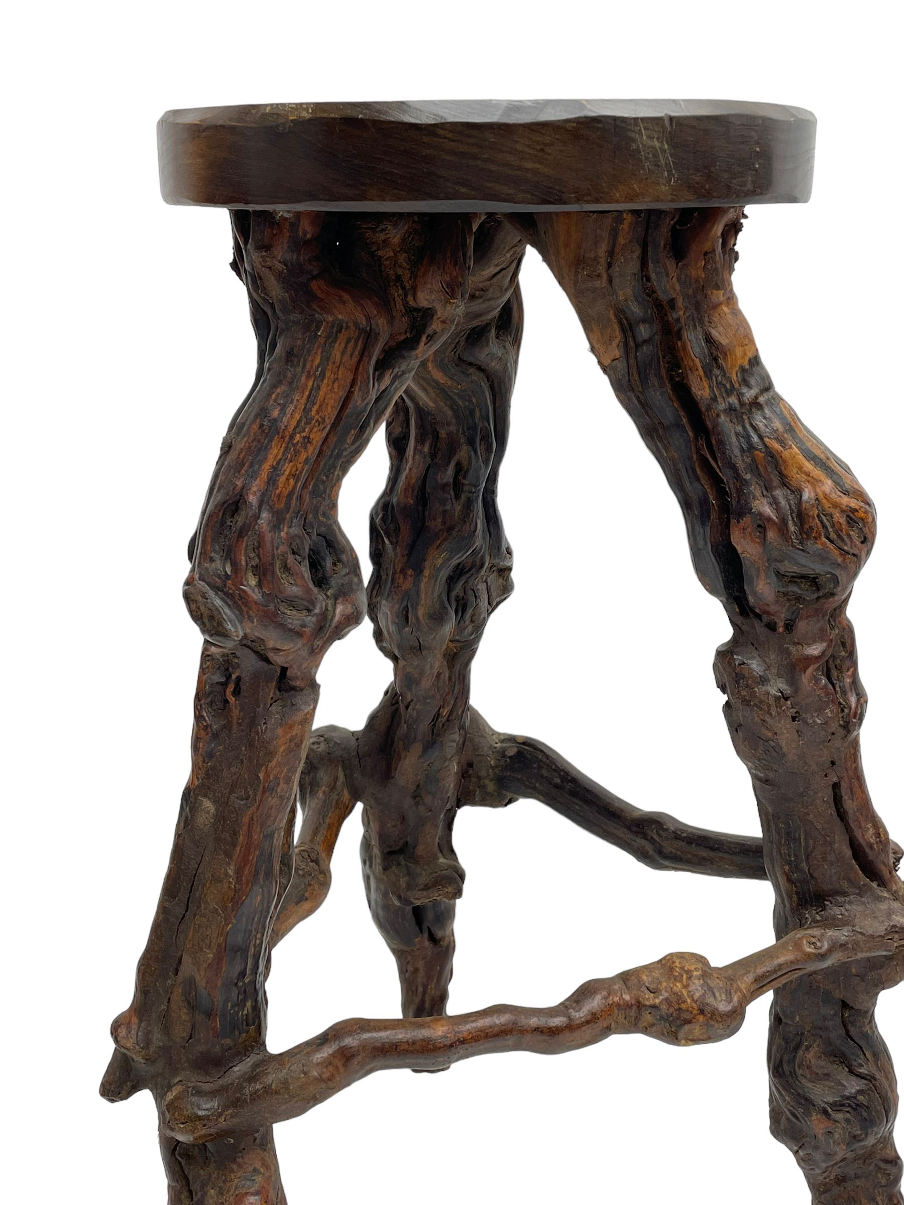 Mid-20th century French grapevine and walnut bow-front wine tasting bar, the curved counter top supported by sculptural grapevine roots, fitted with single shelf and raised on rustic vine feet (W100cm H101cm); with a pair of matching bar stools, the circular top raised on three gnarled root supports united by stretchers (W50cm H70cm)