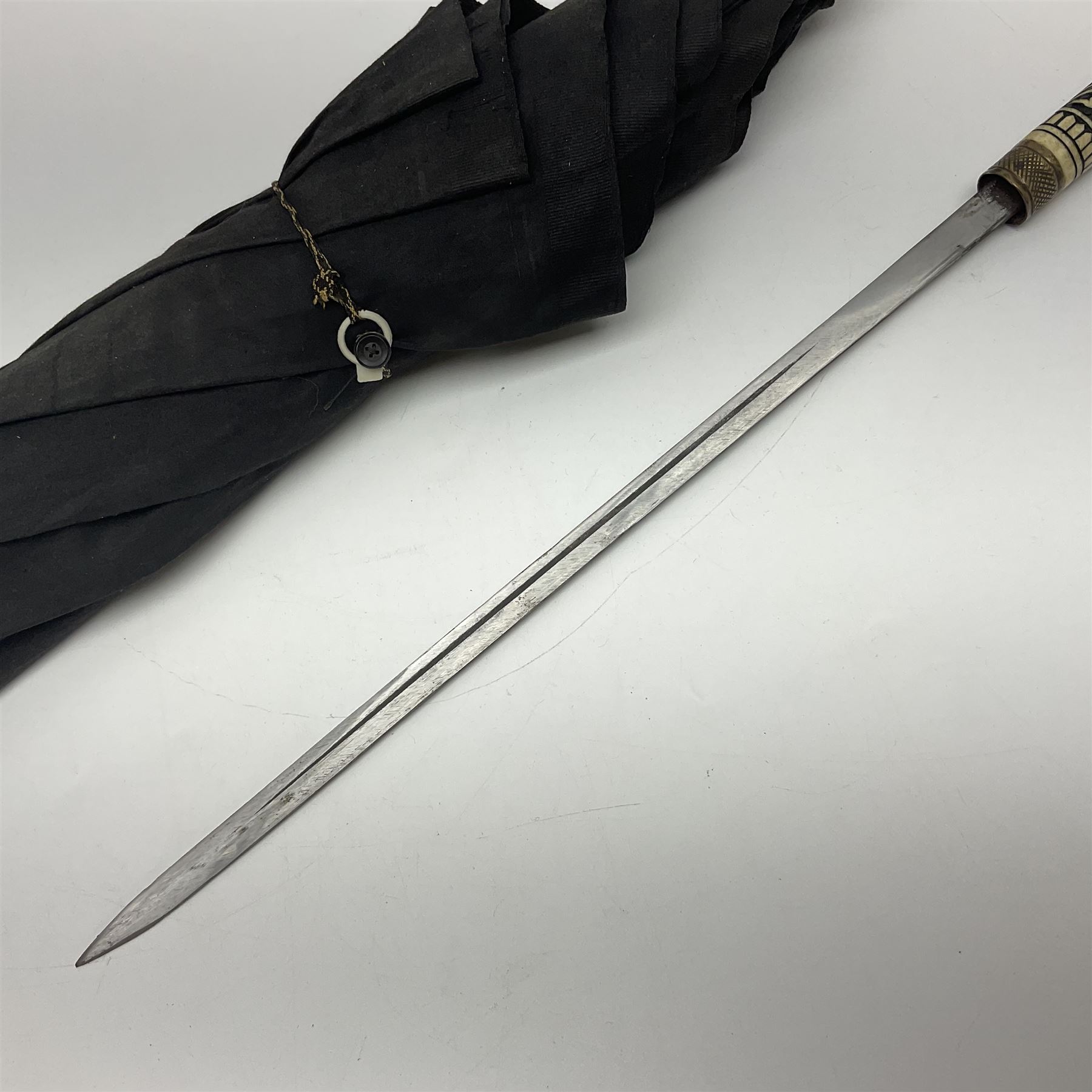 Early 20th century Indian ebonised wooden umbrella sword stick with 36cm blade, carved bone mount and black cloth cover L92cm overall; together with a similar Indian ebonised wooden sword stick with 64cm blade, carved bone mount and brass lion mask pommel L91cm (2)