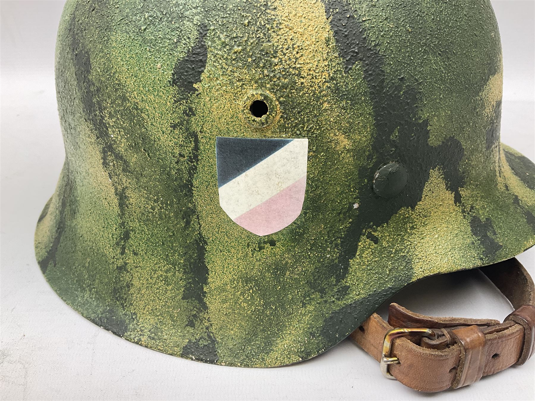 Fully restored German steel helmet, the camouflage painted exterior with two decals and replacement leather liner