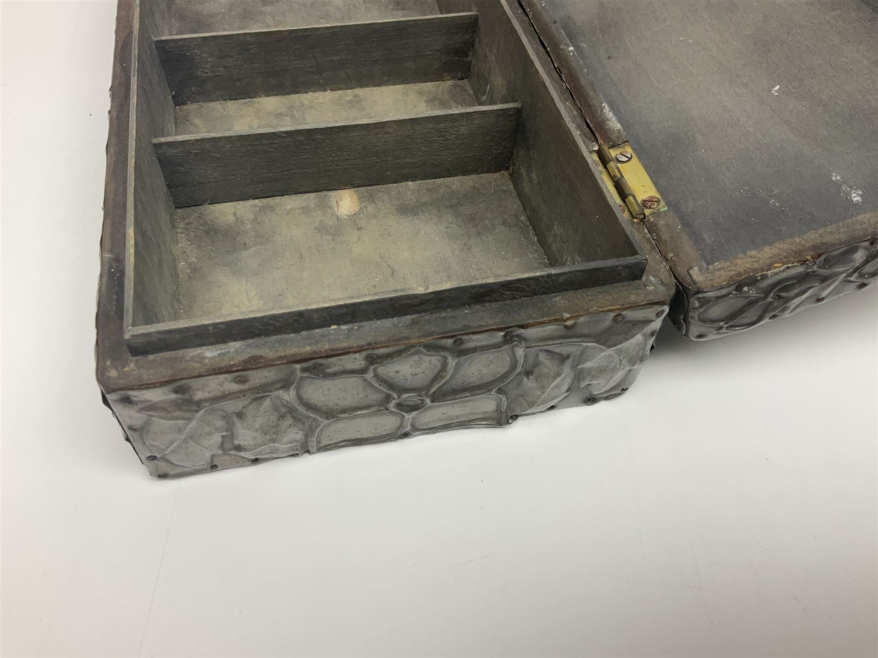 Liberty & Co Tudric pewter cigarette box, of plain rectangular form, with planished decoration to the slightly domed cover, opening to reveal a softwood interior, stamped Made in England 01234 Tudric Solkets beneath, together with another cigarette box, with applied pewter panels repousse decorated throughout with flower heads and leaves, with compartmentalised softwood interior, largest H5.5cm, W23cm