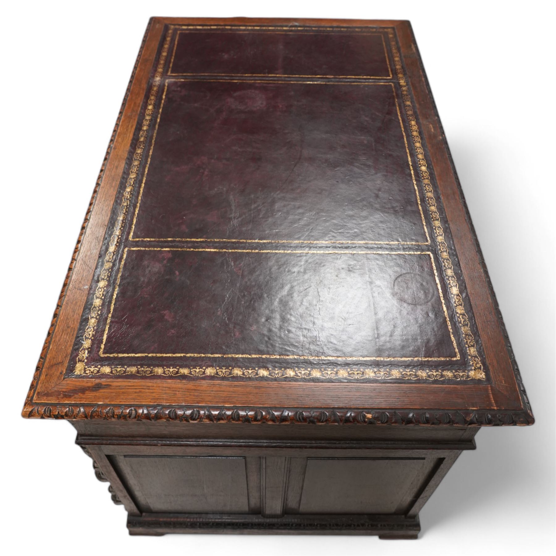 Victorian carved oak twin pedestal desk, moulded and foliate carved rectangular top with leather inset, fitted with nine drawers, each carved with scrolling foliage and lion mask handles, on skirted base 