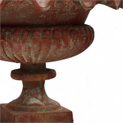 Pair of cast iron garden urns, each of flared form with crinkled edge rims and circular bodies, finished in aged red paint and raised on square bases