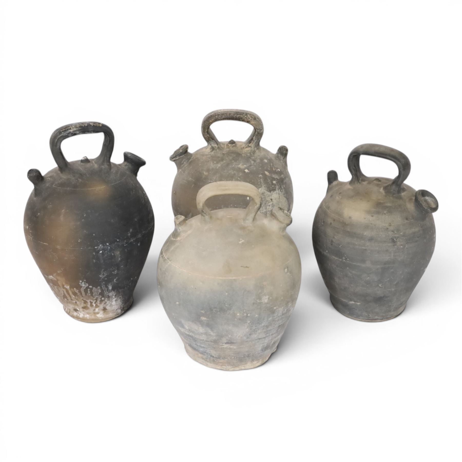 Four 20th century Spanish blackened earthenware botijo or cruche vessels, each of typical baluster form with central loop handle and opposing spout, impressed marks to handles, tallest example H31cm