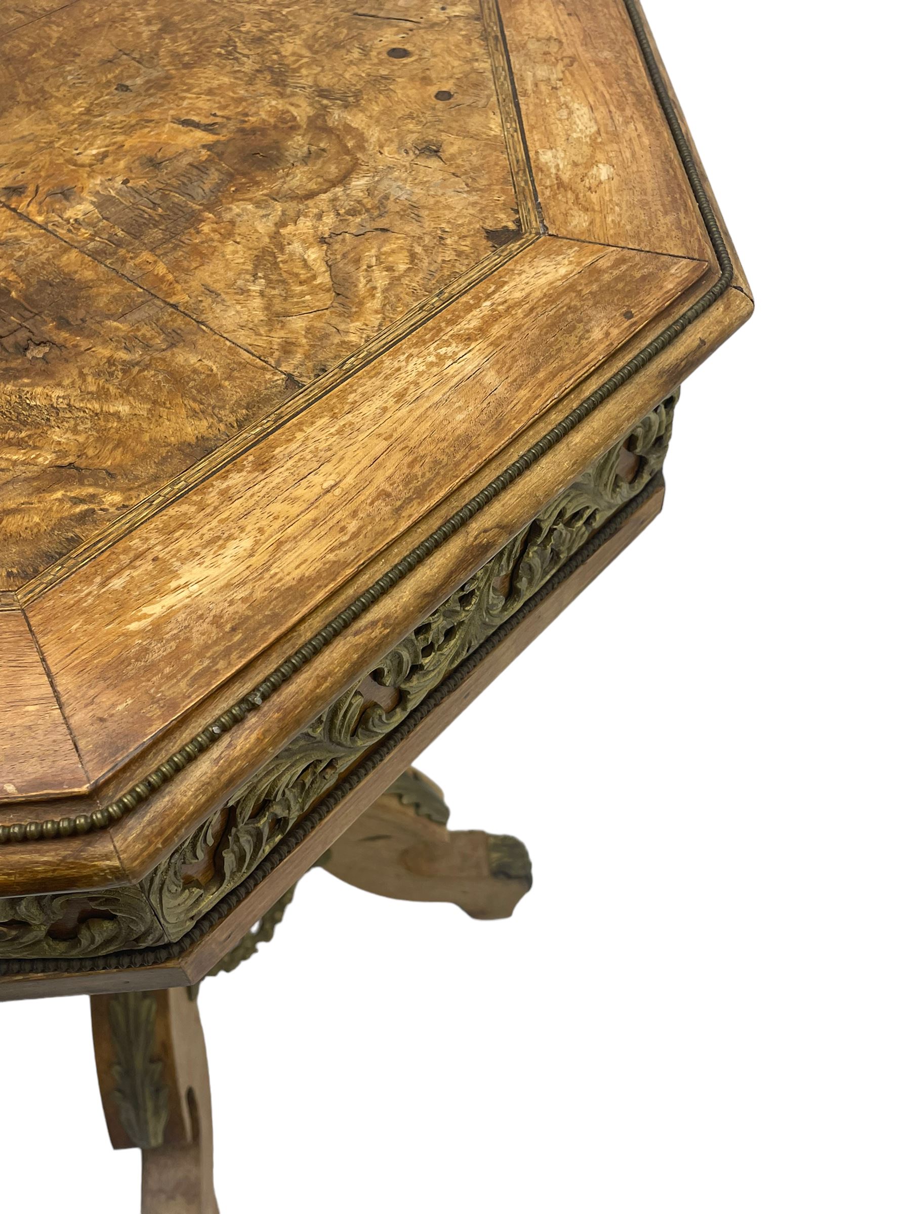 Mid-20th century figured walnut Italian design centre table, octagonal quarter veneered top with cross banding and moulded edge, the skirt decorated with scrolling foliage gilt metal mounts, on turned pedestal mounted with gilt acanthus leaves, quadruple splayed supports with further acanthus leaf decoration