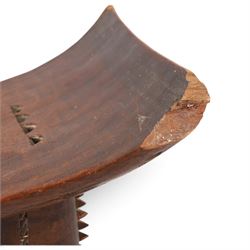 African carved hardwood headrest, having flared edges, raised on a stepped plinth base with further carved detailing, H34cm