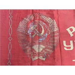 1970s Soviet banner printed in gold on a red ground, roughly translates as 'Transferable Banner - To the winner in the Socialist Competition' and 'Work Study Live by Communism' verso; wreath of wheat ears to either side; tassels on three sides 110 x 155cm