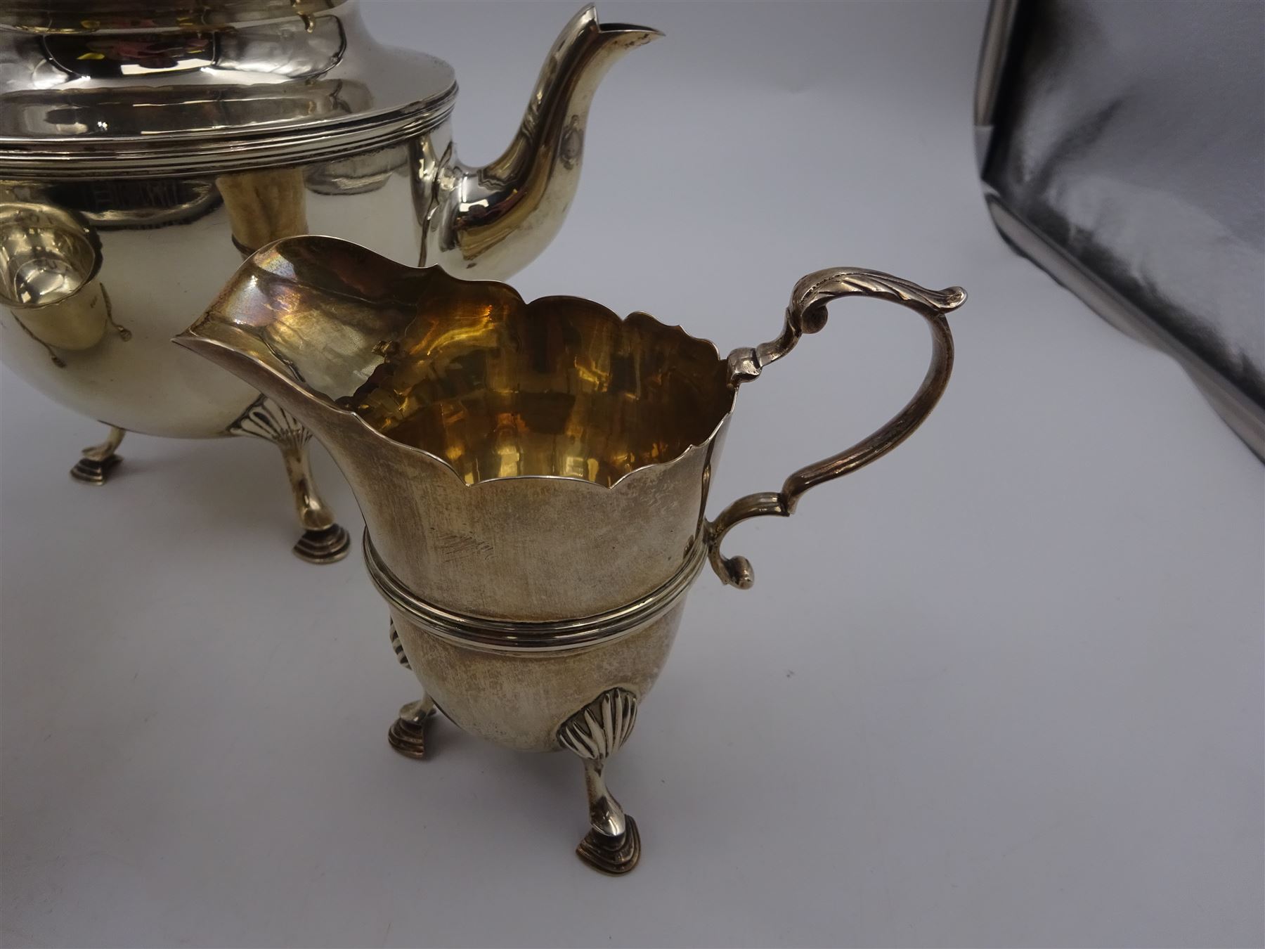 1920s three piece silver tea service, comprising teapot, with ebonised wooden handle and finial, milk jug and open sucrier, all of circular form, with shaped rims, and upon three hoof feet, hallmarked Wakely & Wheeler, London 1922, teapot H19cm