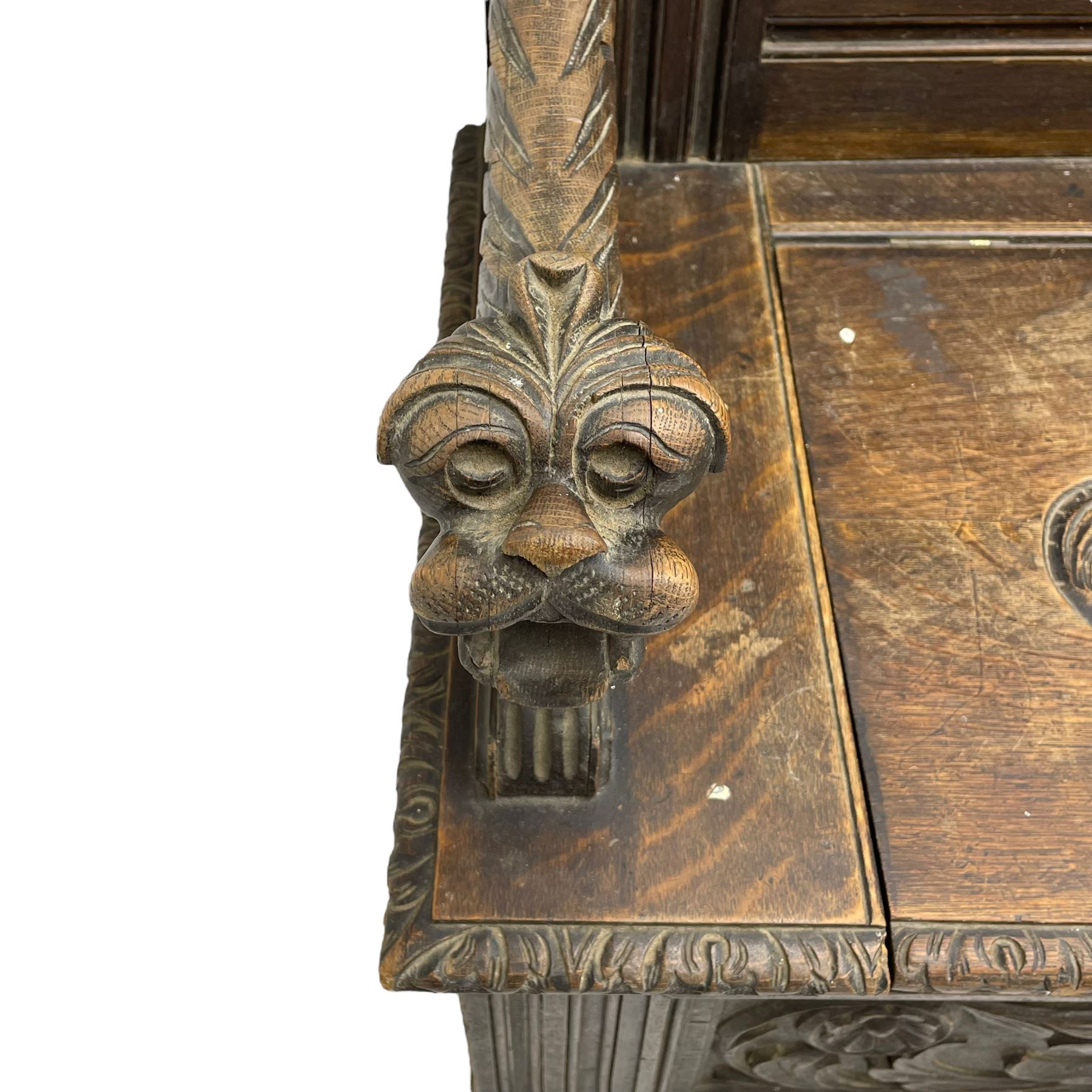 19th century oak hall bench, dentil cresting rail over moulded frame with panelled back carved with fire-breathing mythical beasts and central acanthus leaf motif, scroll carved down-sweeping arms carved with grotesque masks with scrolled foliage and shells, hinged box seat carved with scrolling foliage over panelled front with further carved foliage decoration, on paw carved front feet 