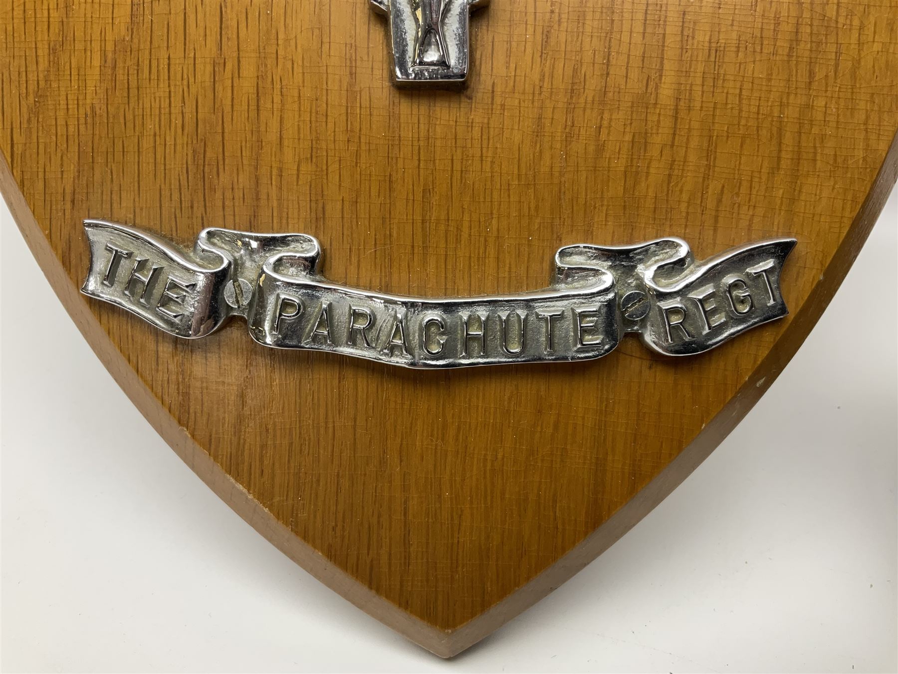 Parachute regiment - chrome crest on oak easel shield; three cloth badges; small silver plated figure; and pin badge; together with 10cm diameter cannon ball etc