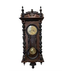 Late 19th cent German wall clock in a mahogany and ebonised case with turned columns and finials, eight-day spring driven movement striking the hours and half hours on a gong, ivorine chapter with a gilt repousse centre, glazed door with a visible gridiron pendulum.