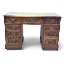 Late 19th century carved oak twin pedestal desk, rectangular top with inset leather writing surface, fitted with nine drawers, carved with scrolling foliate decoration, in three sections