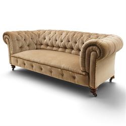 Victorian mahogany framed two seater Chesterfield settee, traditional shape with rolled back and arms over sprung seat, upholstered in buttoned-back neutral fabric, raised on turned front supports with ceramic castors