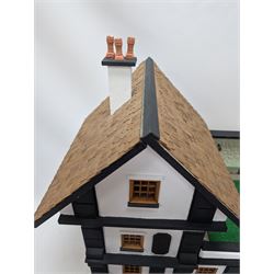 1:24 scale four-storey tudor-style dolls house, with black and white exterior, balcony garden, glazed panelled windows and wooden shingle roof, with decorated interior and wired fireplaces and lighting, H65cm, W58cm, D31cm, 